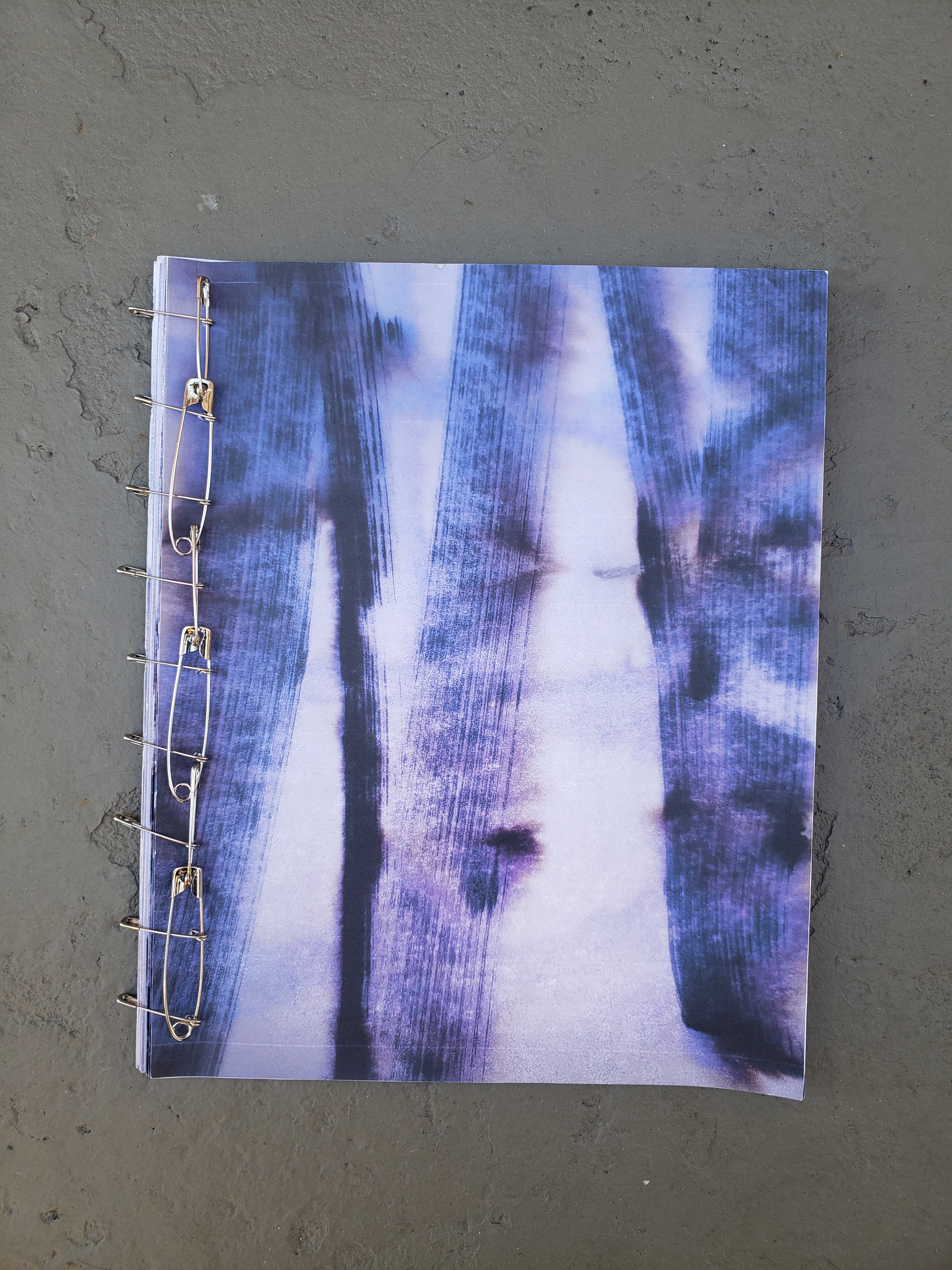 The purple cover of a book binded together with hairpins